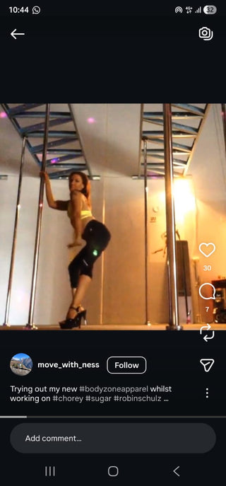 Person posing in a mirror with pole dancing equipment, using social media platform interface.